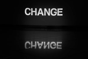 The word change illuminated in white and reflected on a tiled floor