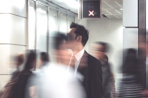 A blurred, moving conference crowd with stationary man in suit