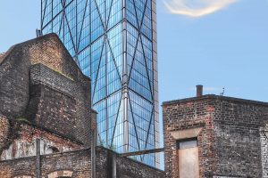 View of London with  old, derelict buildings in foreground and tall, modern, shiny skyscraper behind.